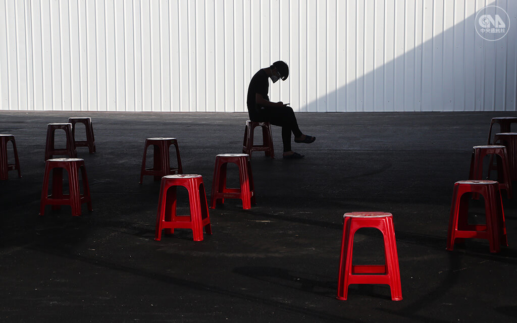台灣5月中旬至6月中，每天本土新增個案破百例，大多集中於雙北地區。新北市在多處設篩檢站提升篩檢量能，一名篩檢陽性的民眾在板橋江翠篩檢站等待車輛接駁準備隔離。